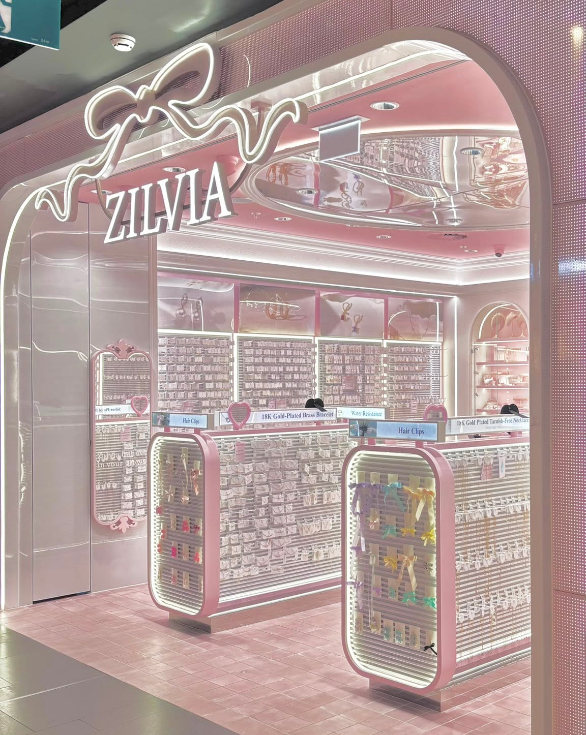 A ZILVIA jewelry store interior with pink walls, illuminated arch framing the entrance, display counters, shelving, and a polished floor. The brand name ZILVIA is prominently visible above the entrance.